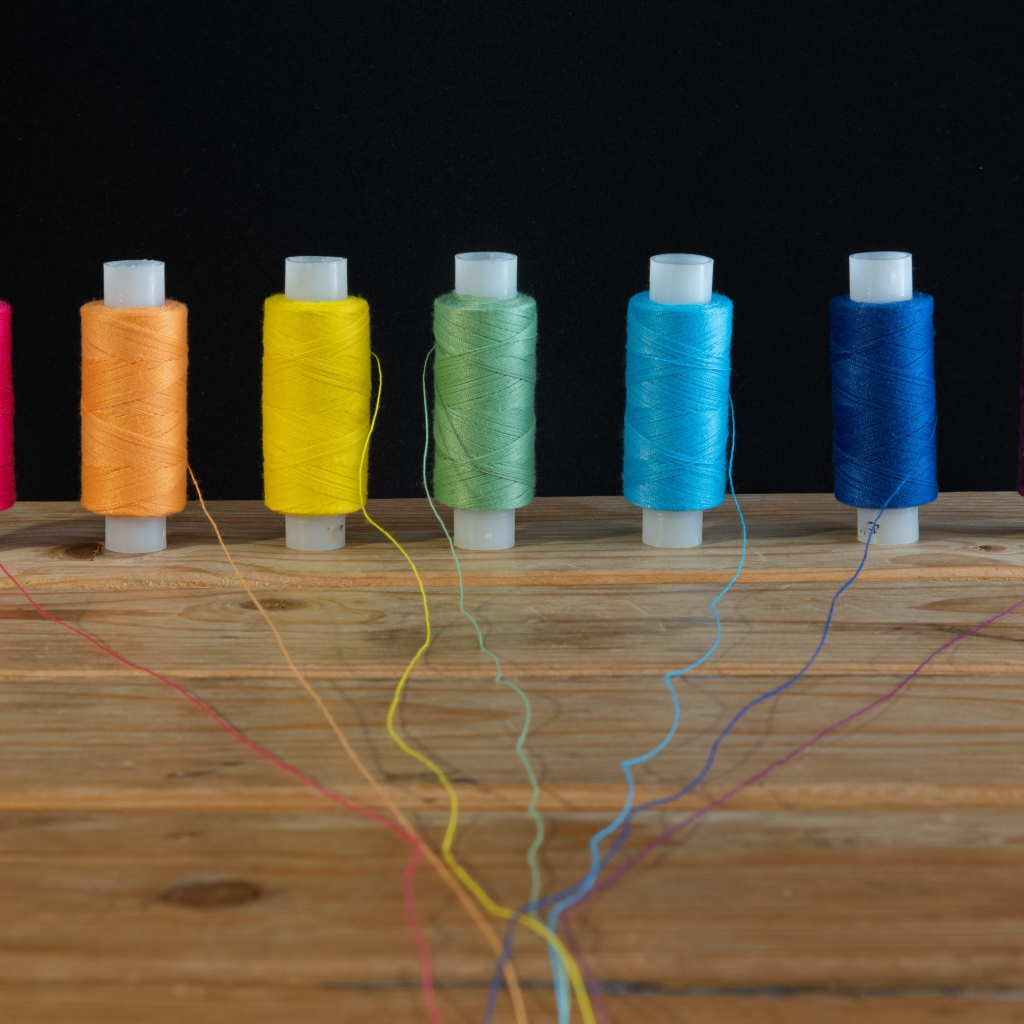 Катушки с разноцветными нитками на черном фоне 