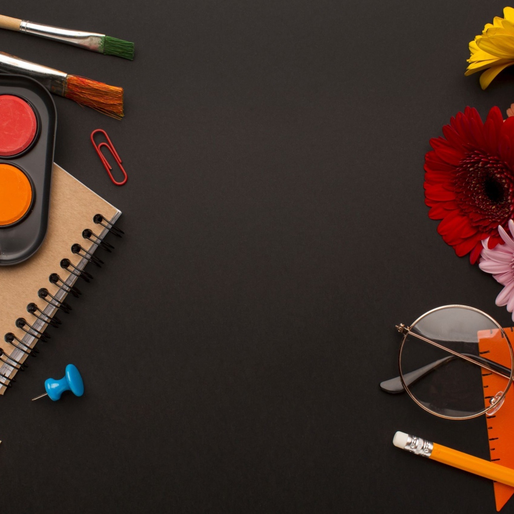 Канцелярские предметы, очки и герберы на черном фоне 