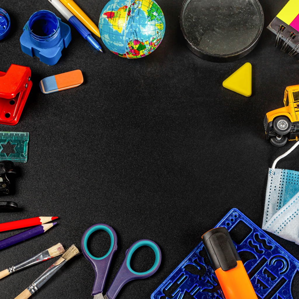 Канцелярские предметы, игрушки и маска на черном столе 