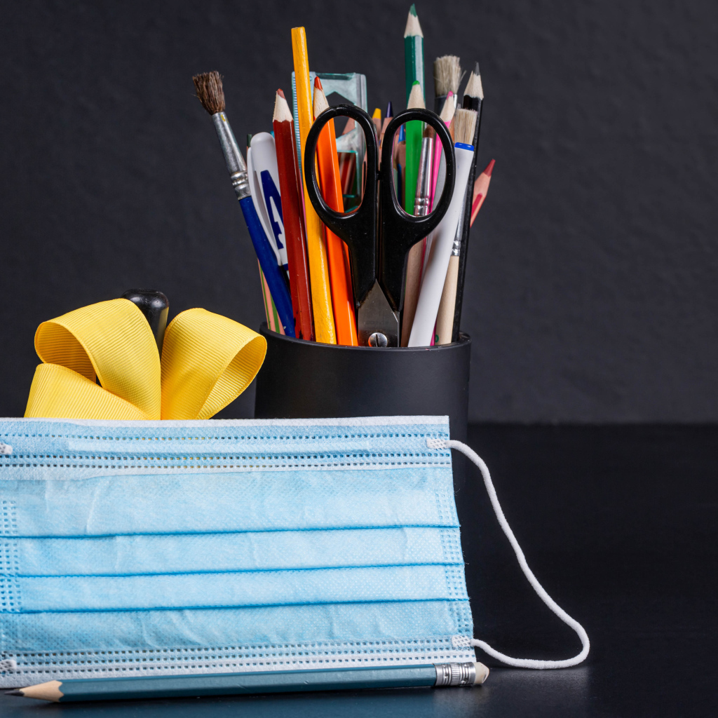 Канцелярские предметы на столе с медицинской маской