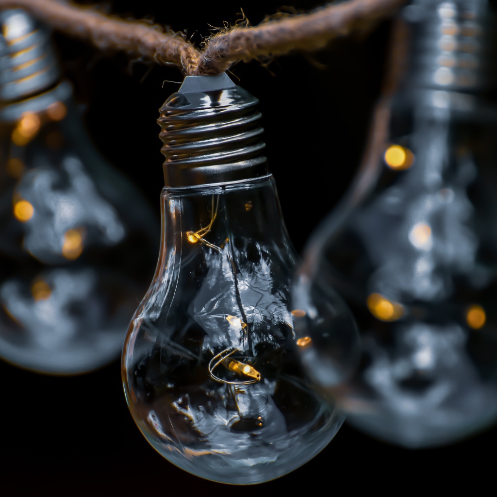 Три лампочки висят на веревке на черном фоне