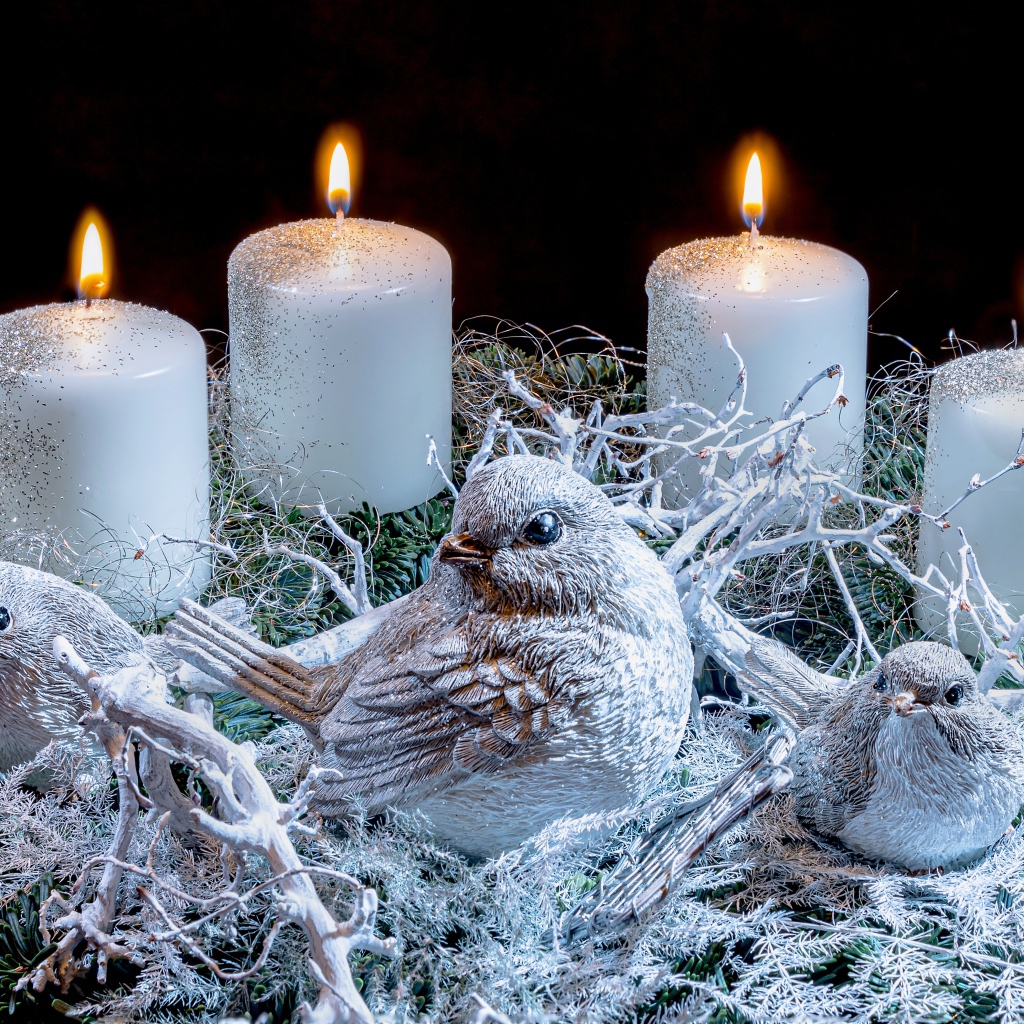 Три зажженные свечи со статуэтками птицами 