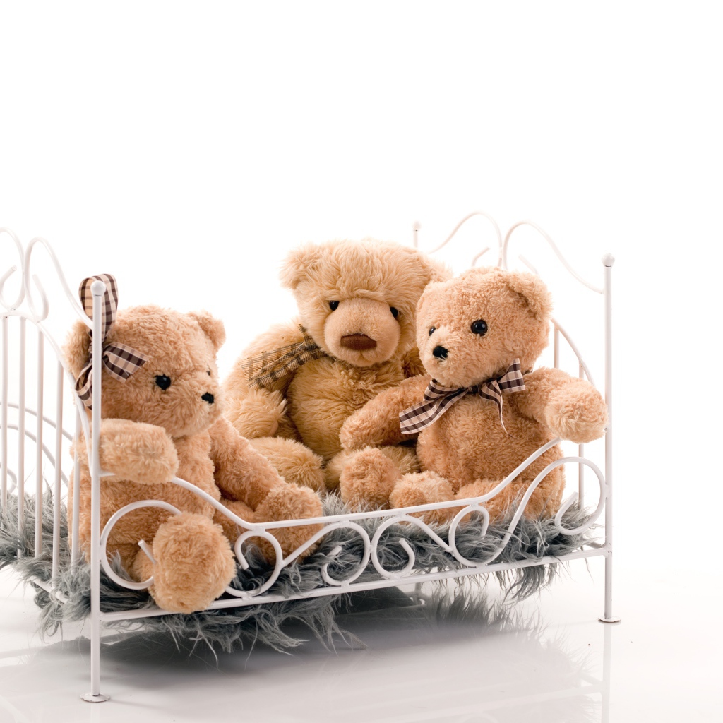 Three toy bears on the bed on a white background