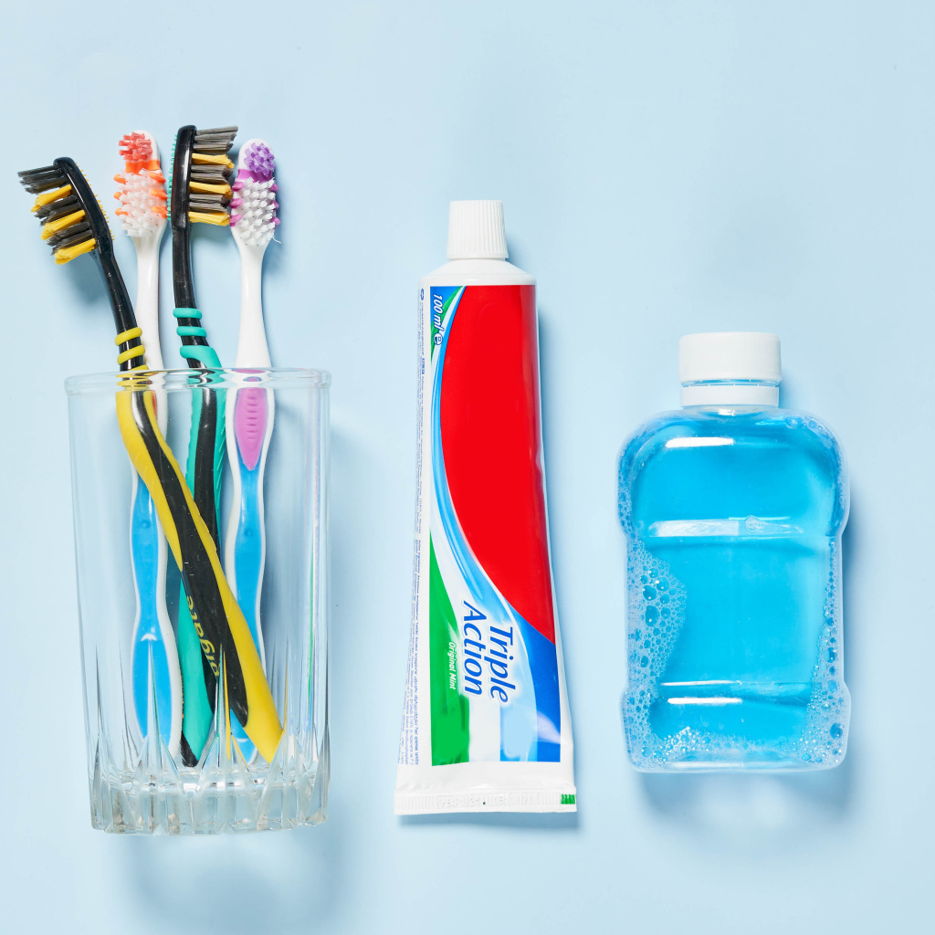 Зубная паста с щетками и ополаскивателем на сером фоне 