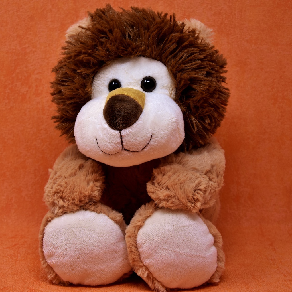 Игрушечный лев на фоне стены