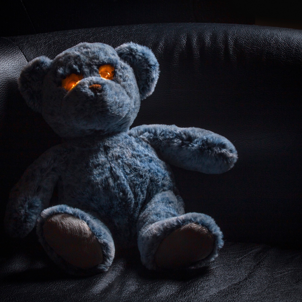 Игрушка со светящимися глазами на черном диване