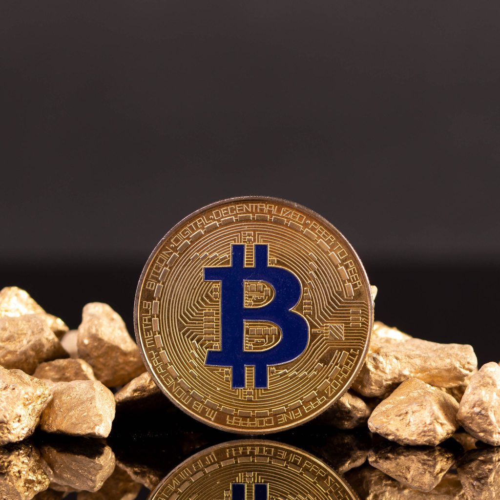 Bitcoin coin with pieces of gold on gray background