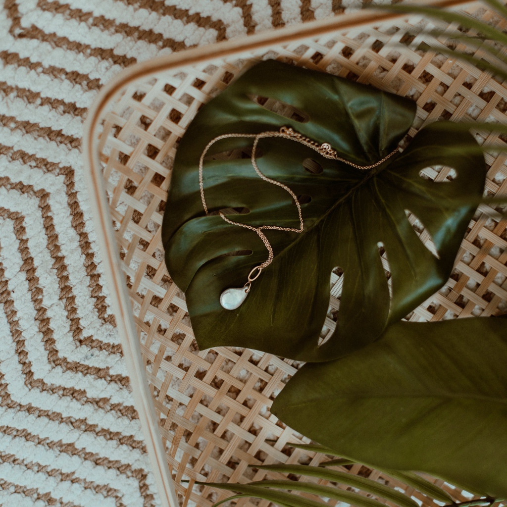 Золотое украшение лежит на большом зеленом листе