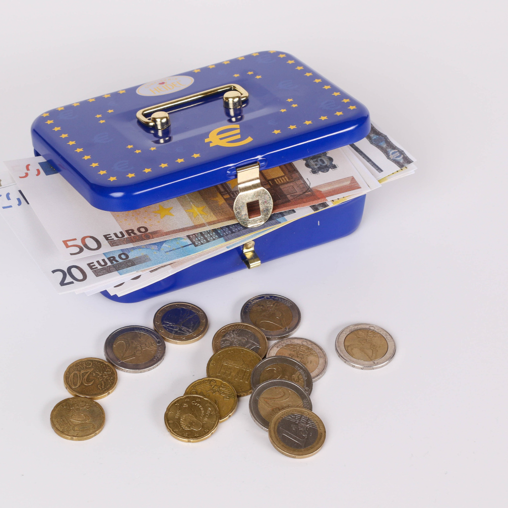 Синяя копилка чемодан с деньгами и монетами на сером фоне