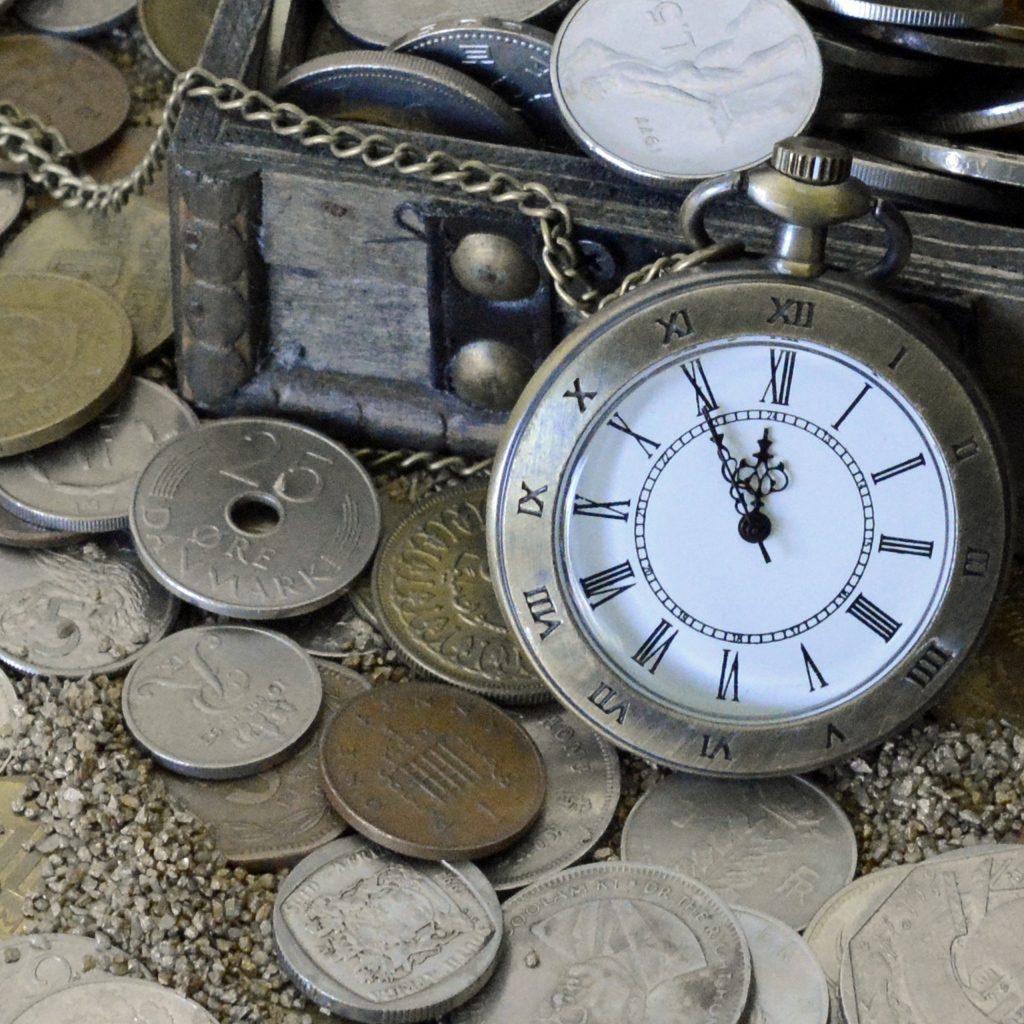Много монет и карманные часы на песке
