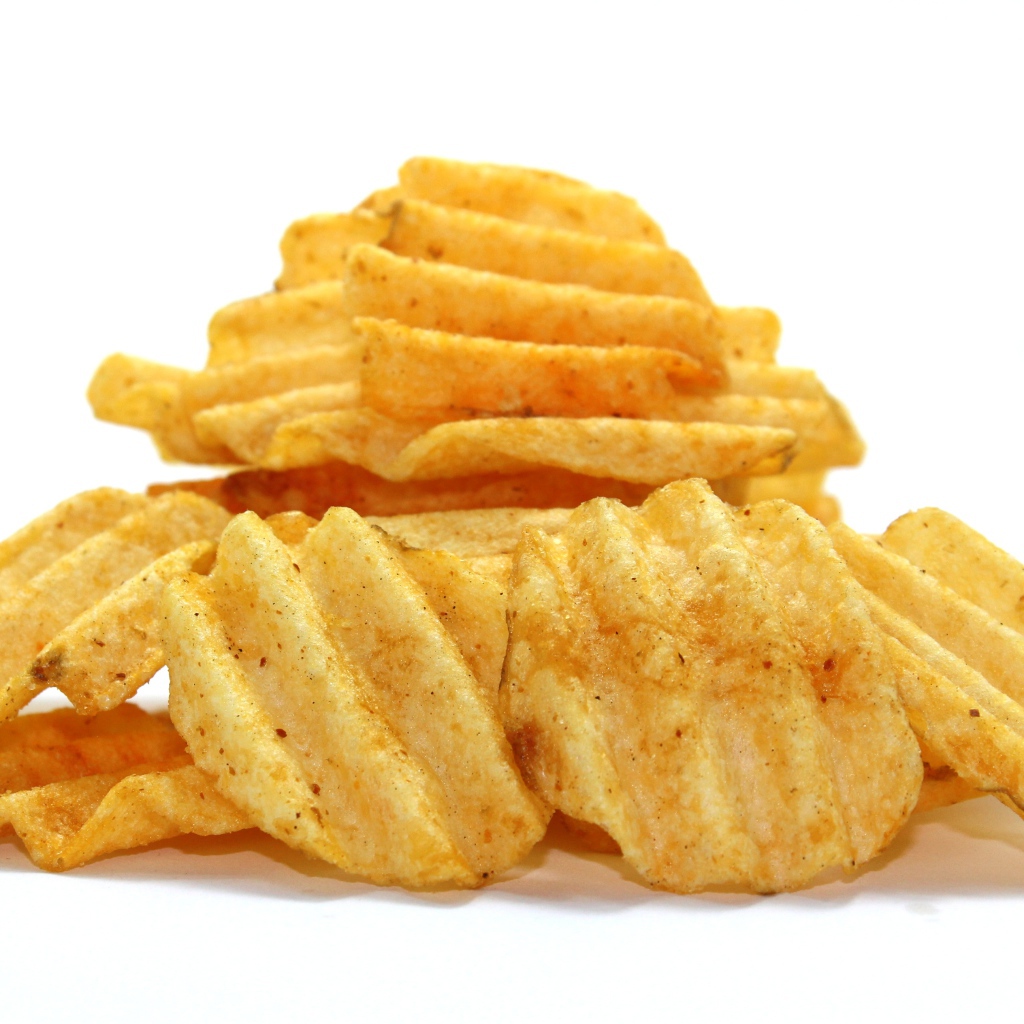 Аппетитные картофельные чипсы на сером фоне