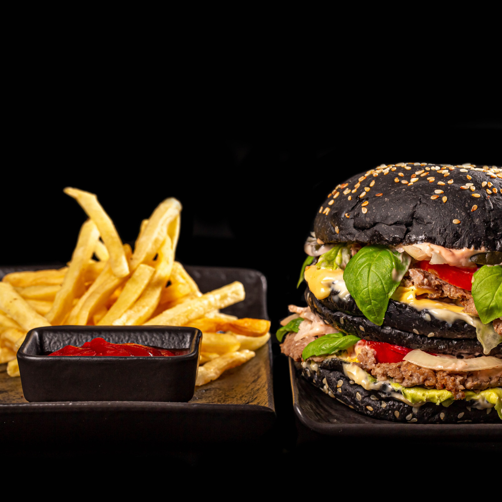 Большой черный гамбургер с картофелем фри и кетчупом 