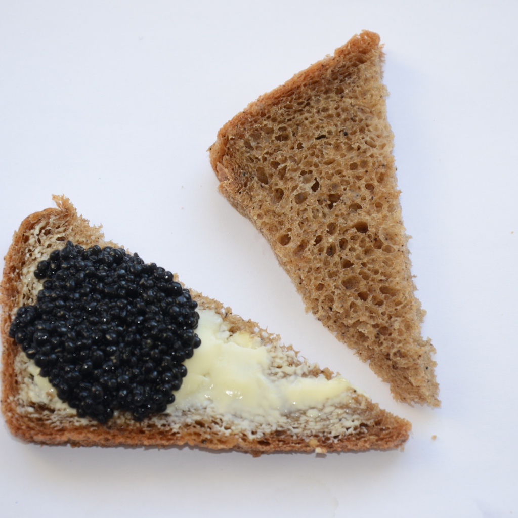 Бутерброды из черного хлеба с черной икрой на сером фоне