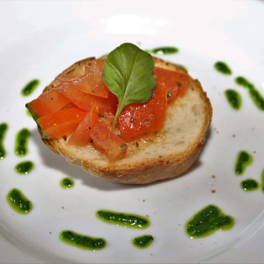 Брускетта на тарелке с помидорами и соусом