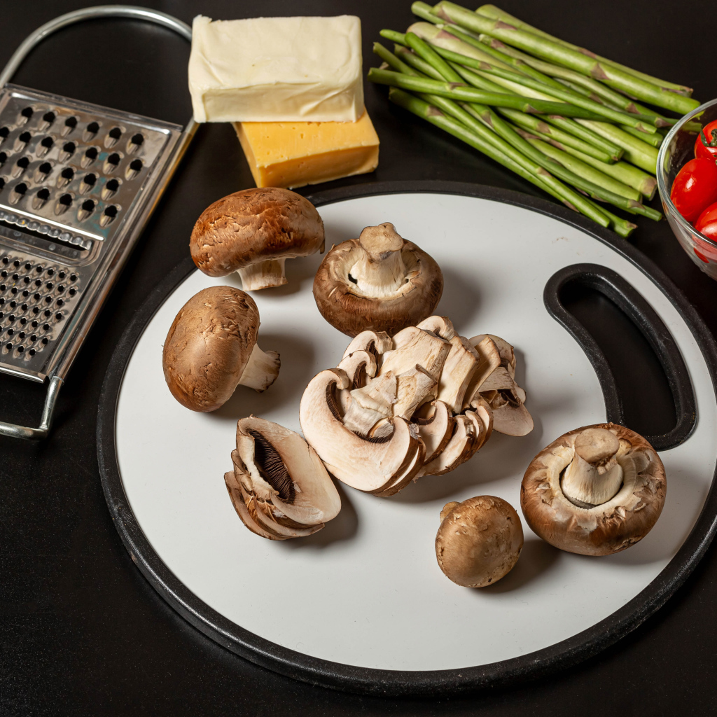 Шампиньоны на столе со спаржей и помидорами 