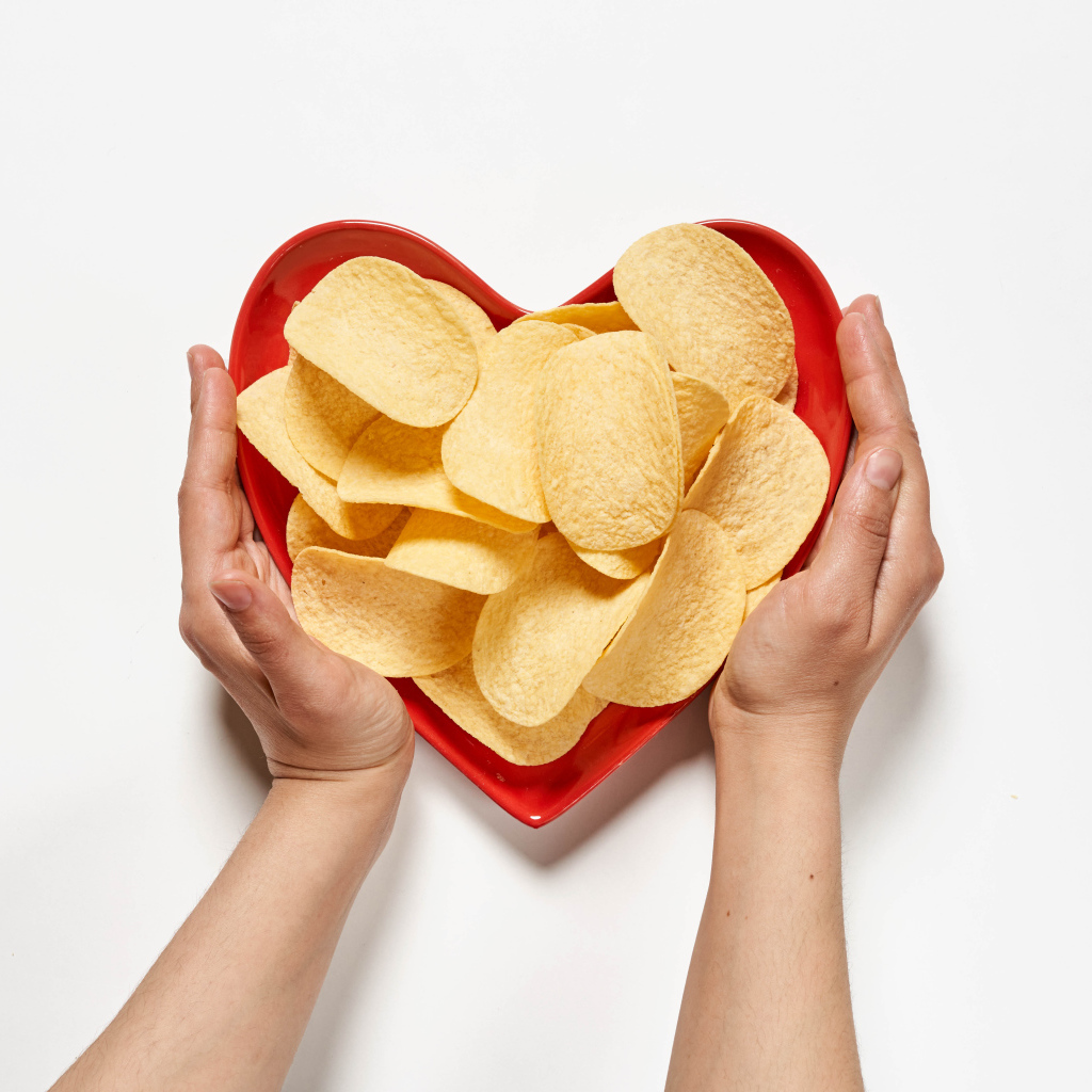 Чипсы в красной тарелке на белом фоне