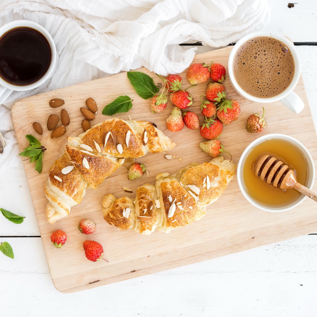 Круассаны на столе с орехами, клубникой и кофе