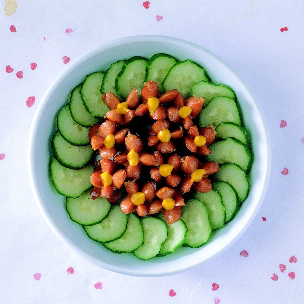 Огурцы с сосисками в тарелке на столе