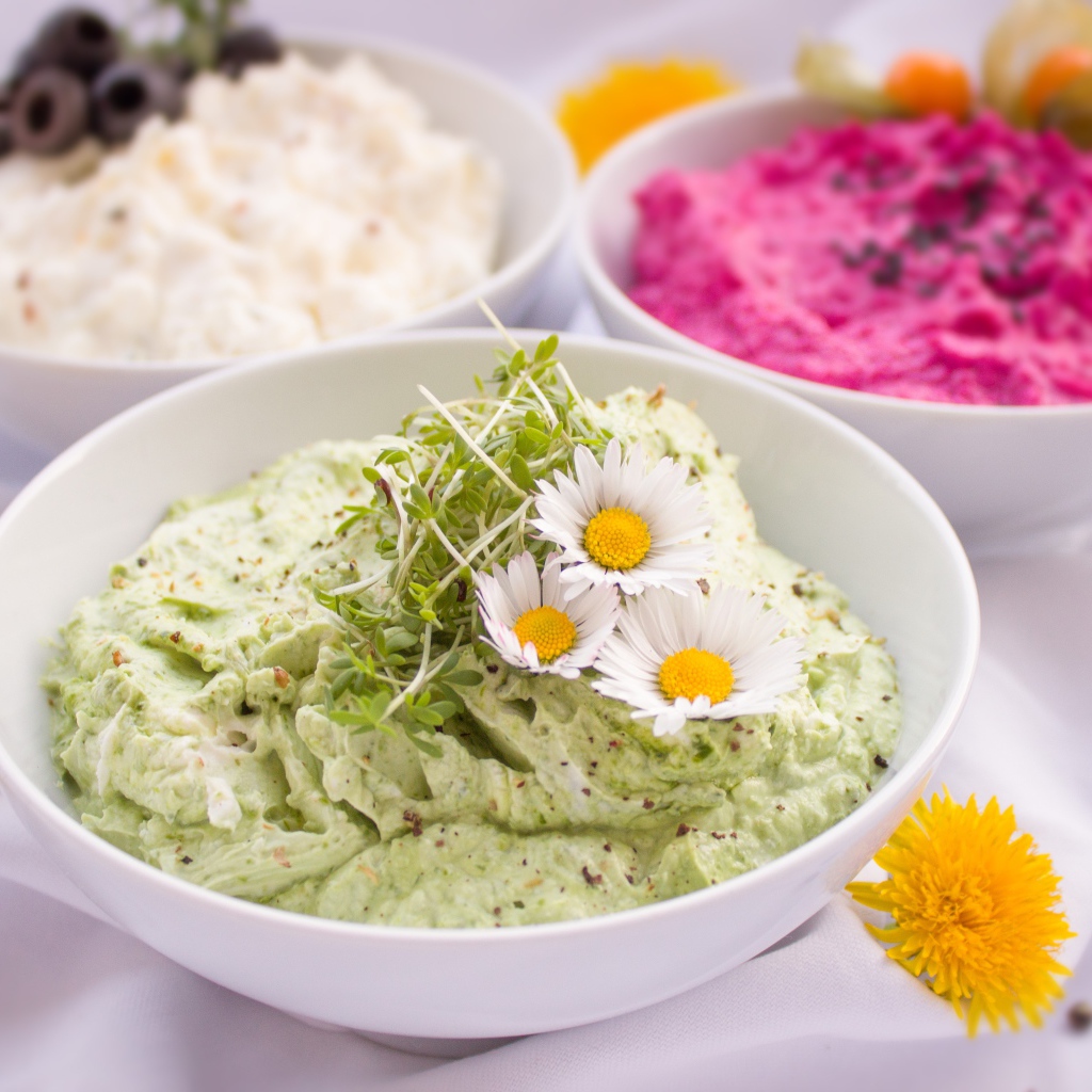 Вкусные салаты в белых мисках на столе с цветами