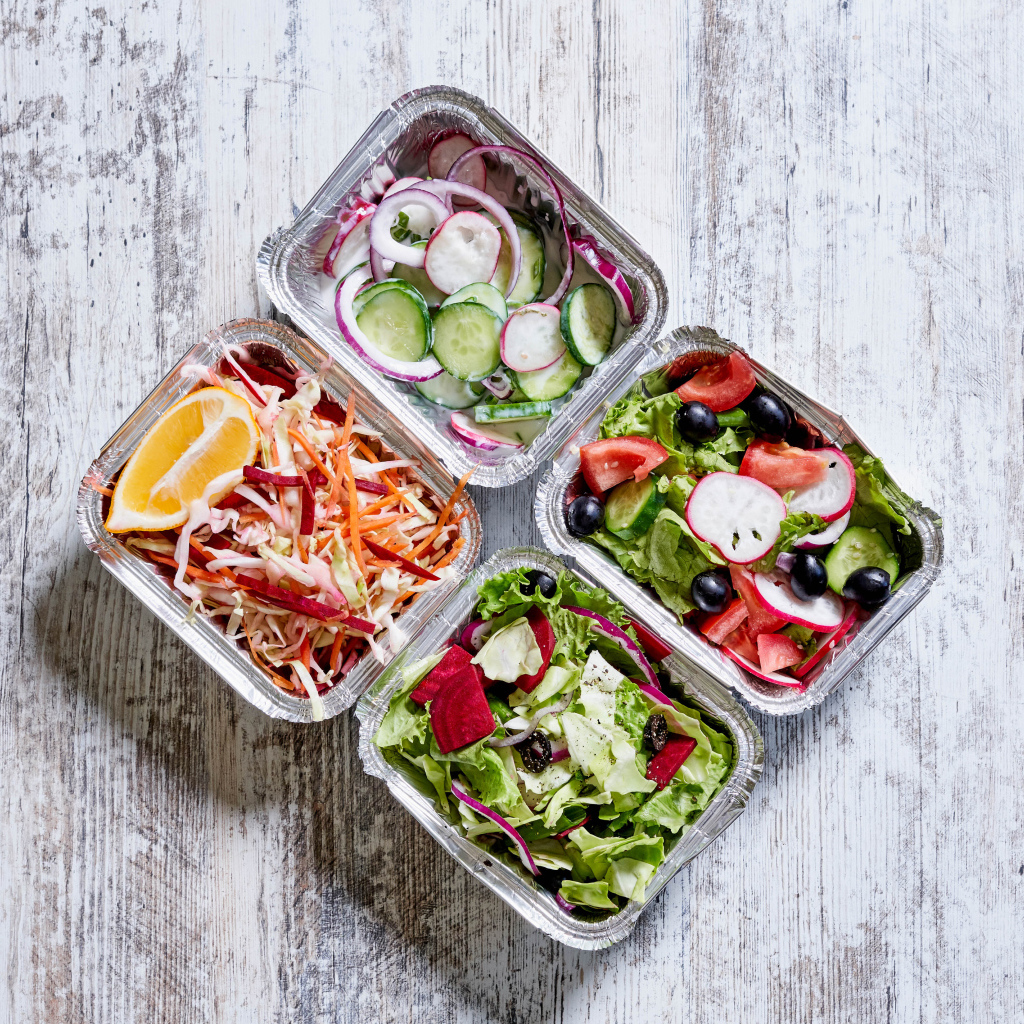 Разные овощные салаты в тарелках на сером столе 