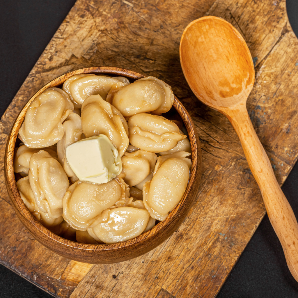 Пельмени в деревянной миске с маслом