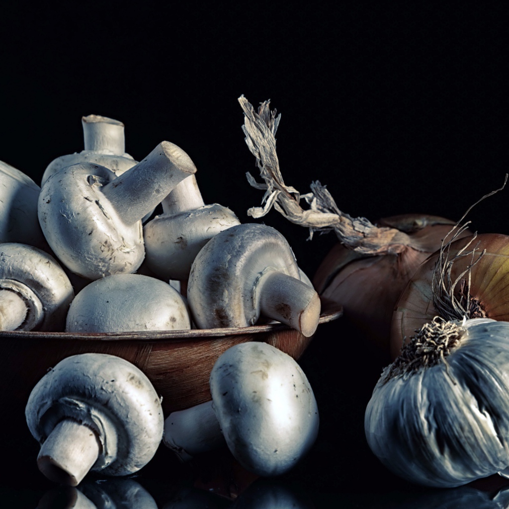 Свежие шампиньоны с луком и чесноком на черном фоне