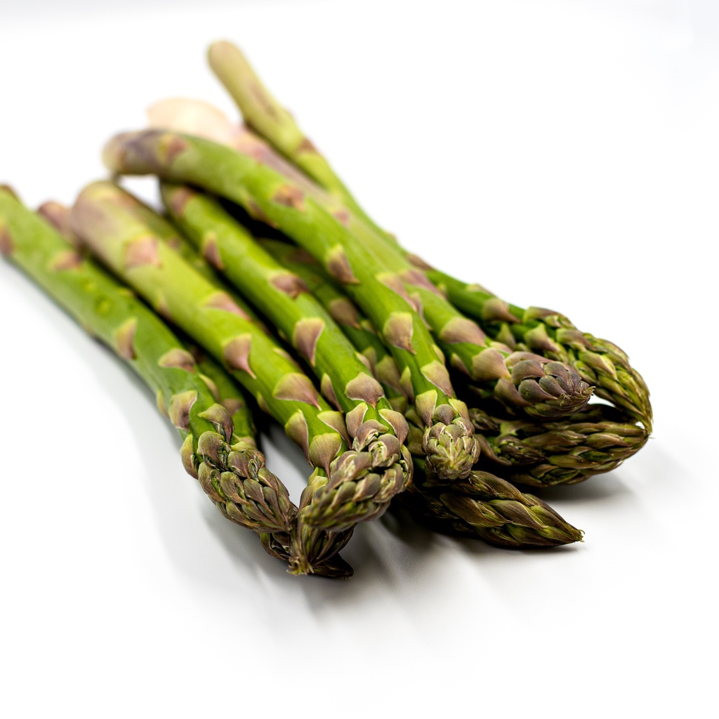 Свежая зеленая спаржа на белом столе