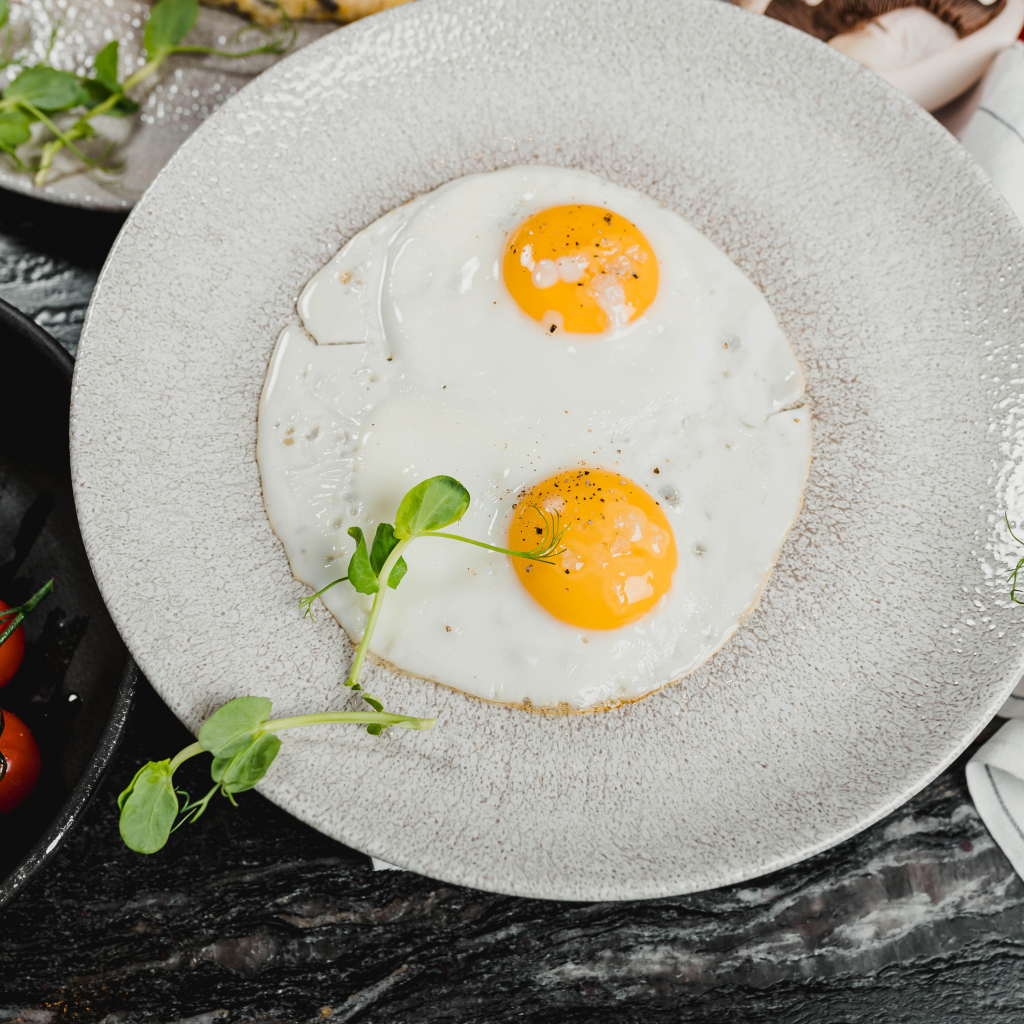 Яичница глазунья на большой серой тарелке