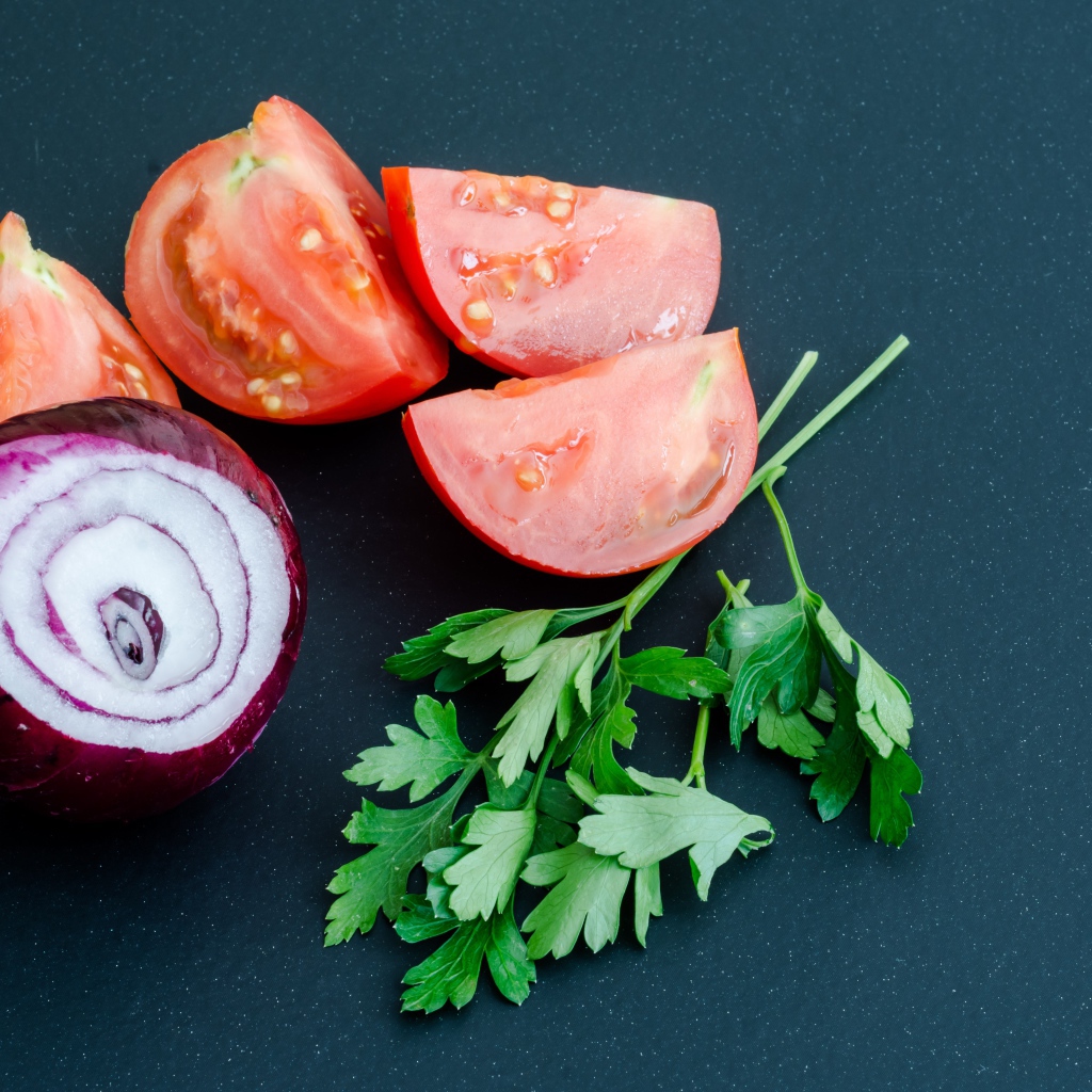 Лук, помидоры и петрушка на сером столе