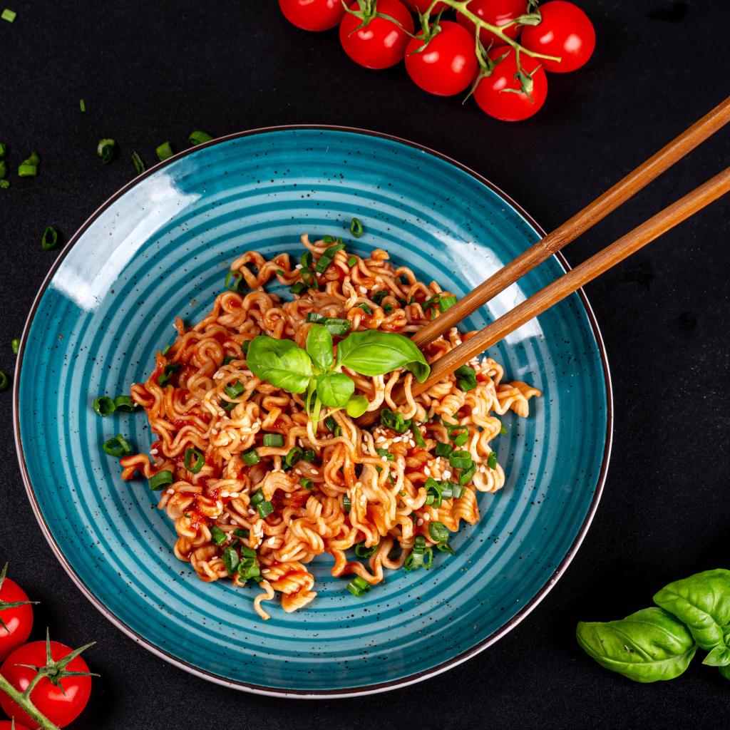 Макароны в соусе на столе с помидорами