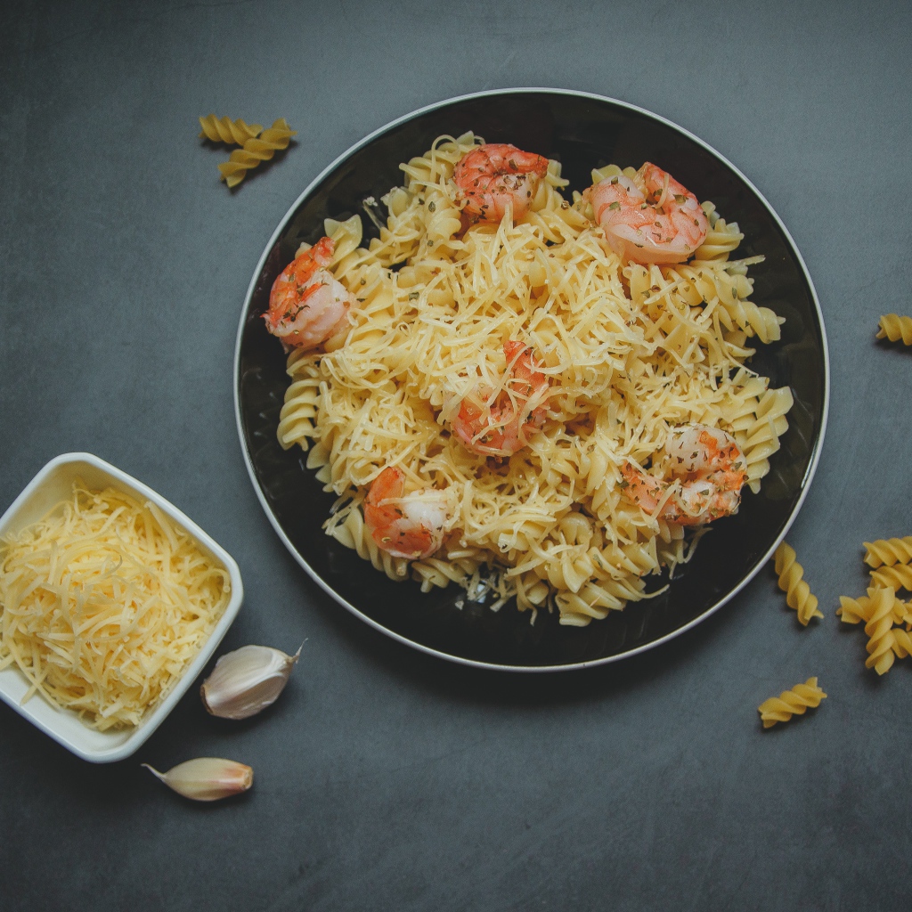 Макароны на тарелке с сыром и креветками