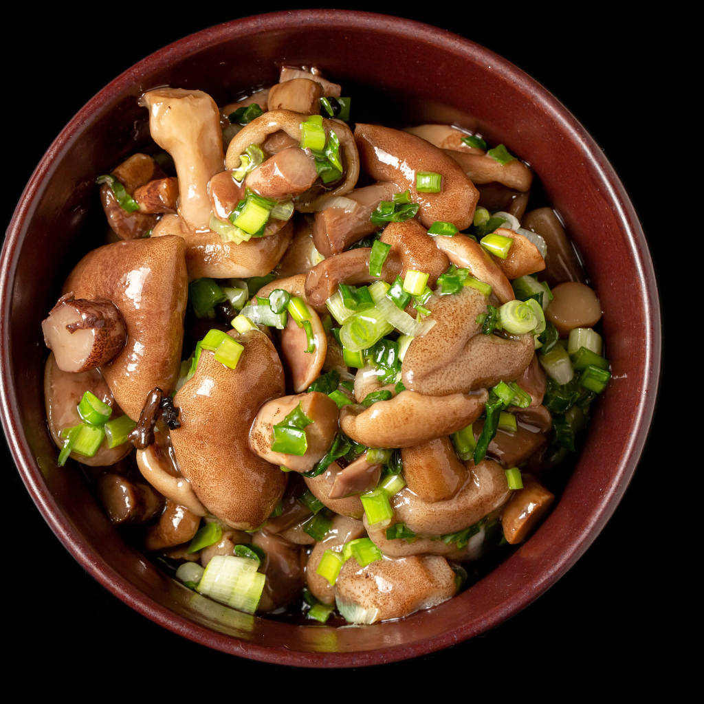 Маринованные маслята с зеленью в тарелке