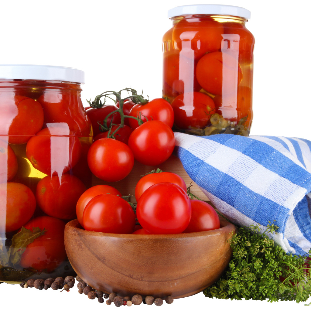 Маринованные помидоры в банках на столе со свежими