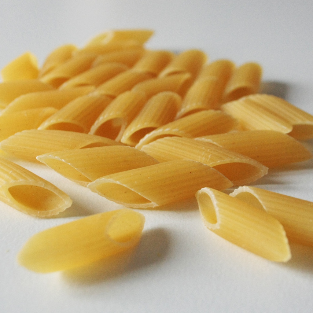 Сырые желтые макароны на сером фоне