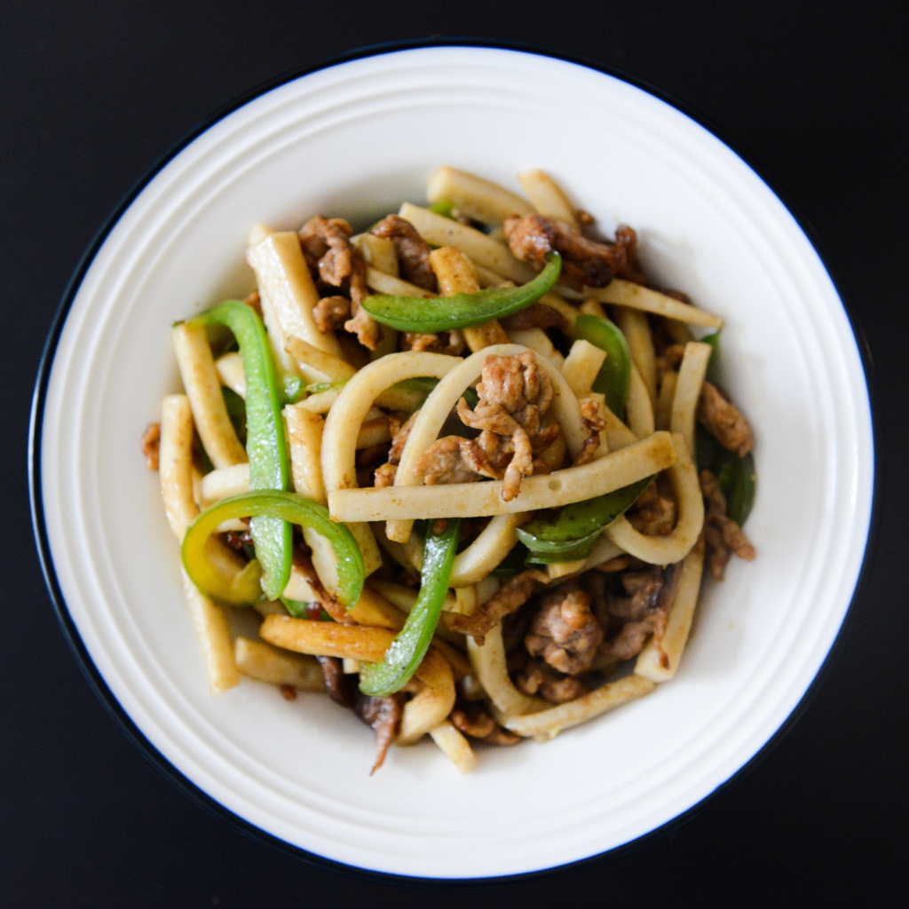 Салат с мясом в белой тарелке на черном фоне