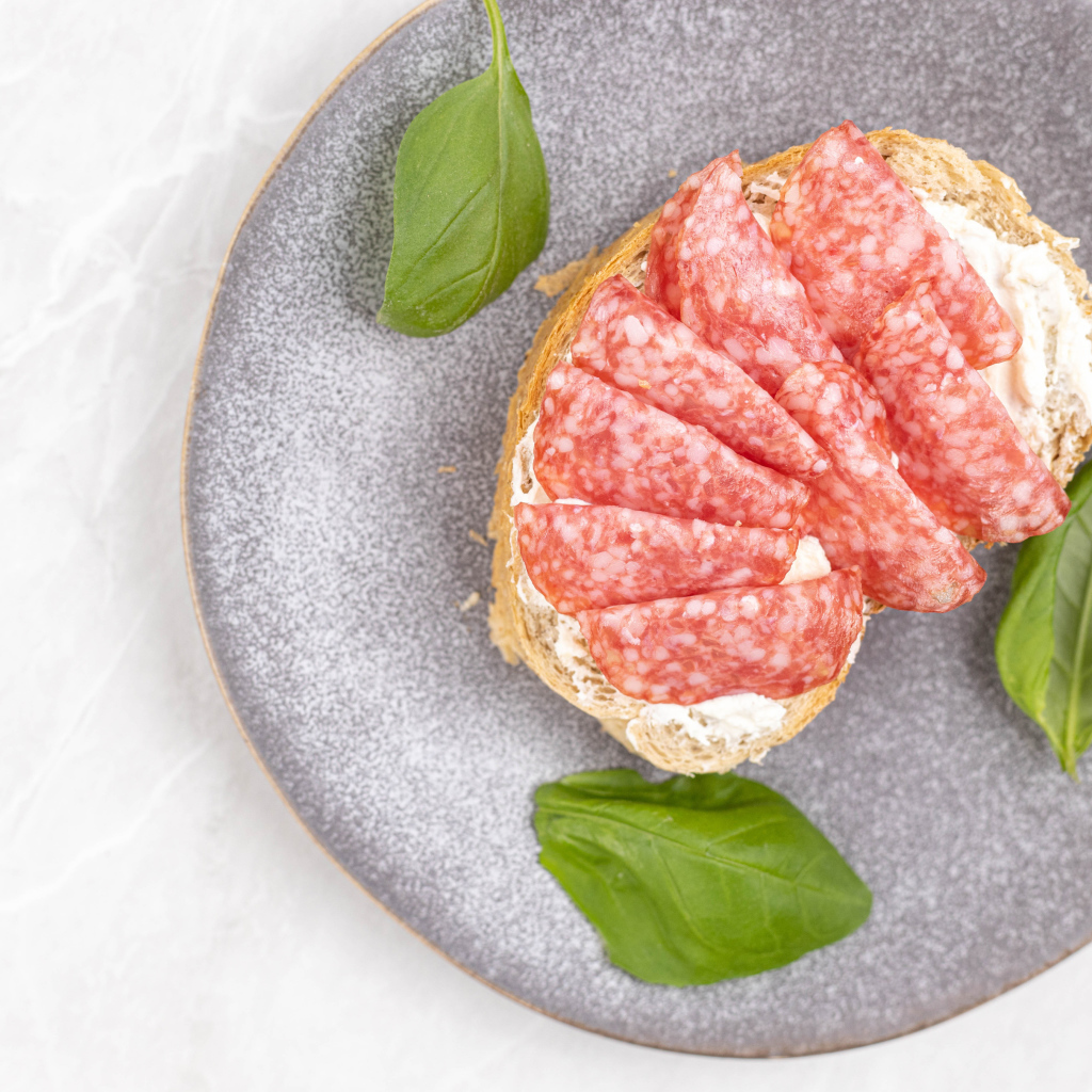 Бутерброд с маслом и колбасой на тарелке