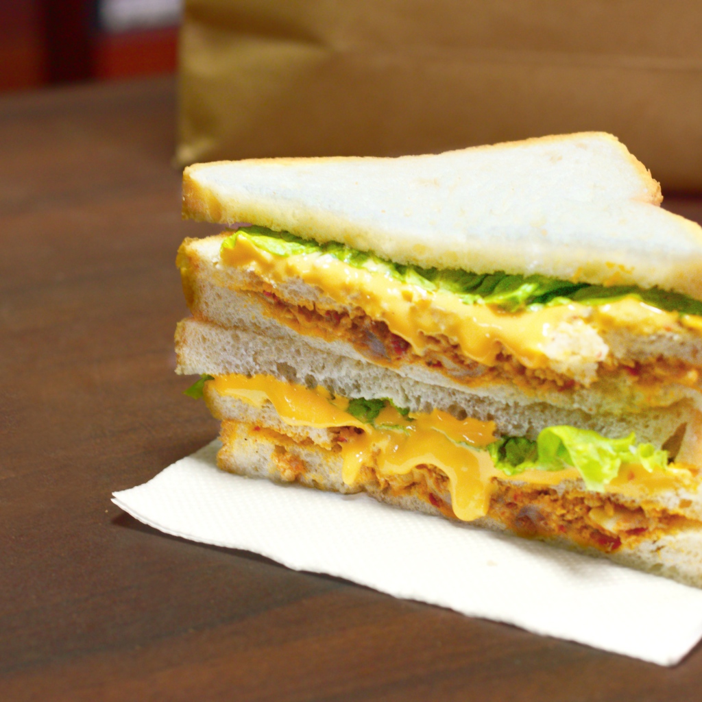 Сэндвич с сыром и листьями салата на столе