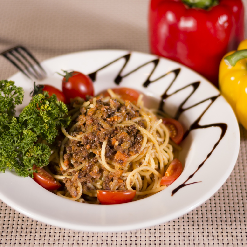Спагетти с фаршем и помидорами в тарелке 