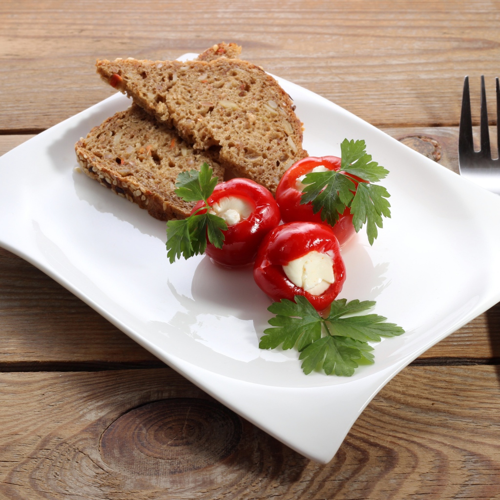 Фаршированный перец на большой белой тарелке с хлебом