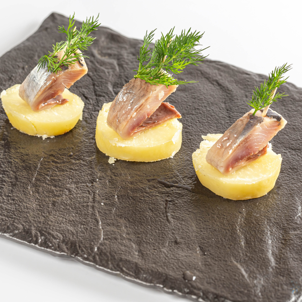 Три куска вареного картофеля с сельдью и укропом