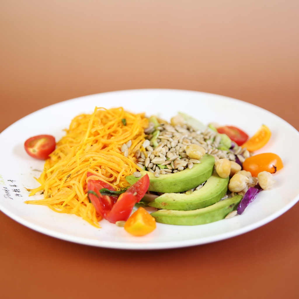 Овощи в белой тарелке на оранжевом фоне 