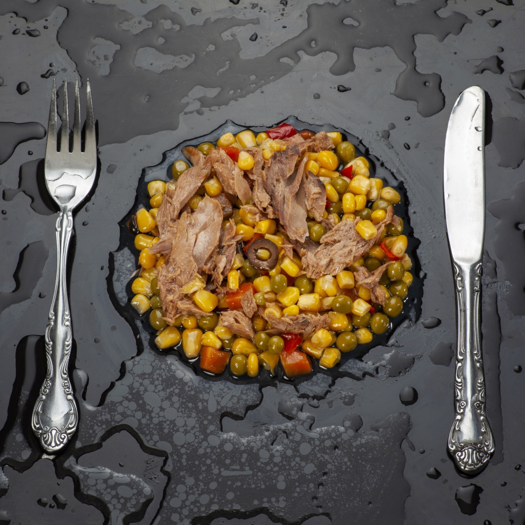 Овощи с мясом и столовыми приборами на черной поверхности