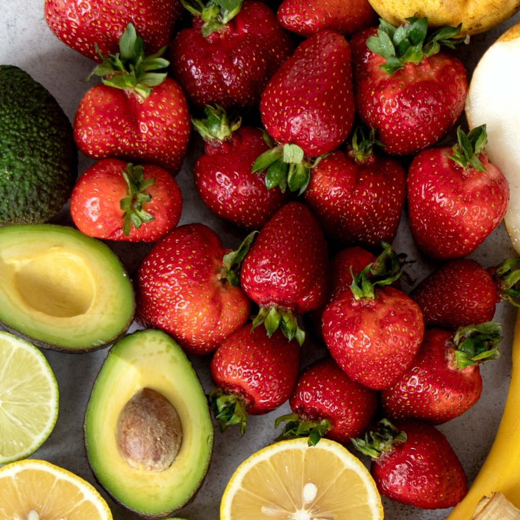Авокадо, клубника,лимон и груша на сером столе 