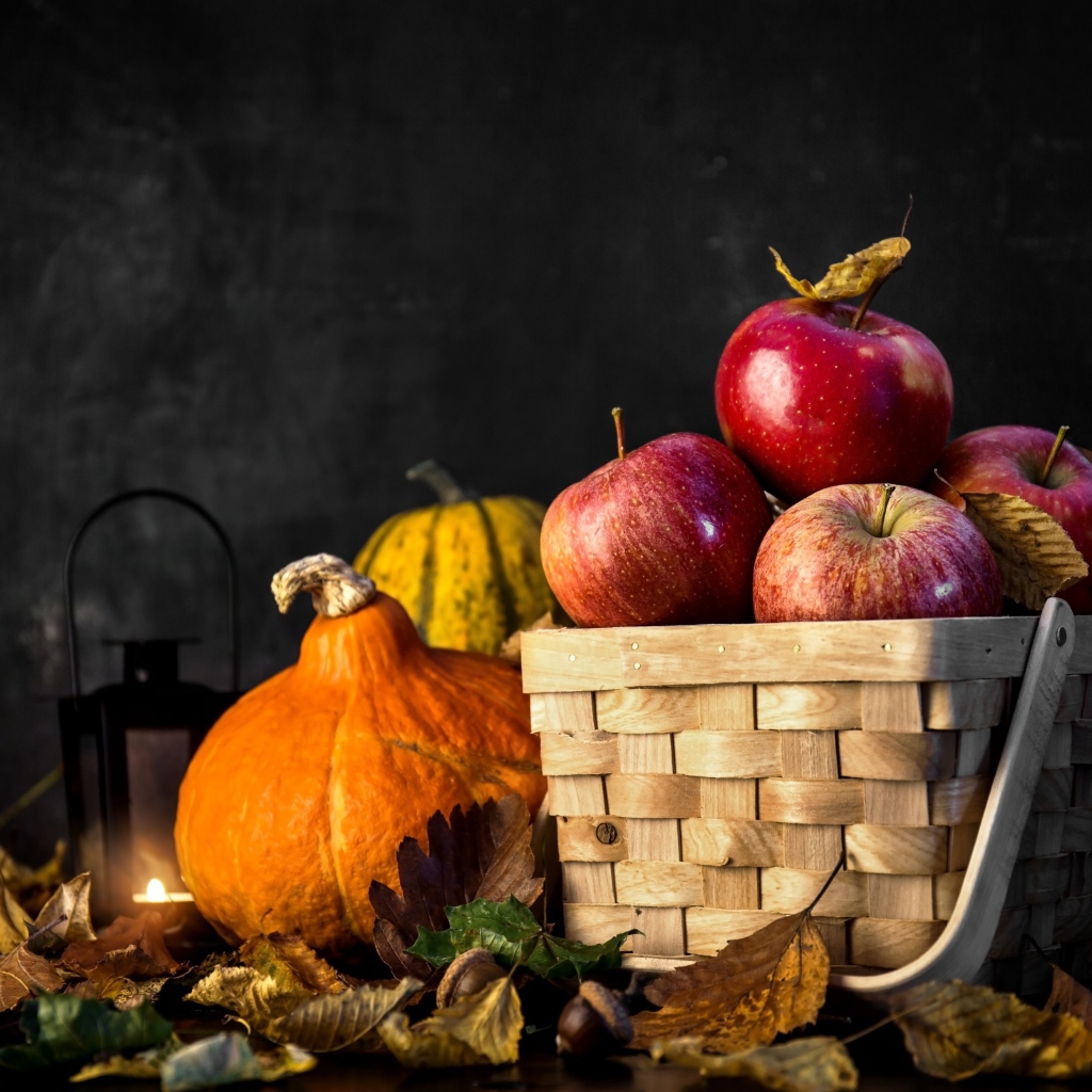 Корзина красных яблок на столе с тыквой