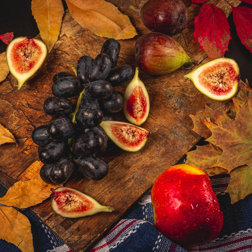 Синий виноград и плоды инжира на столе с листьями