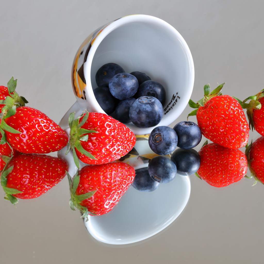 Чашка с ягодами черники и клубники на столе