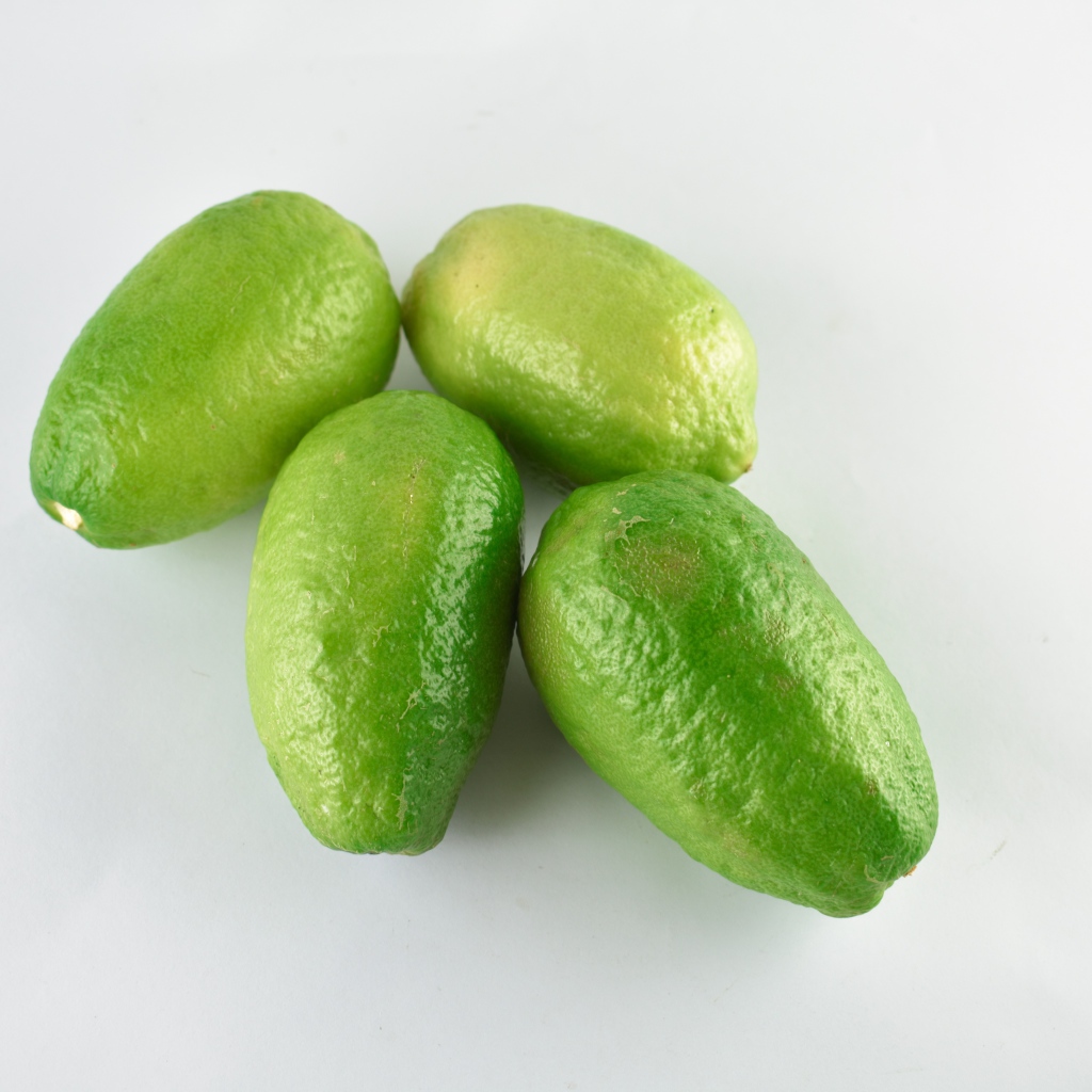 Четыре зеленых лимона на белом фоне