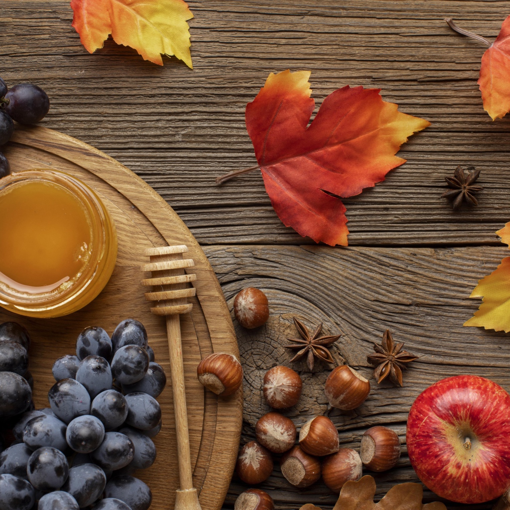 Мед на столе с виноградом, орехами и яблоками