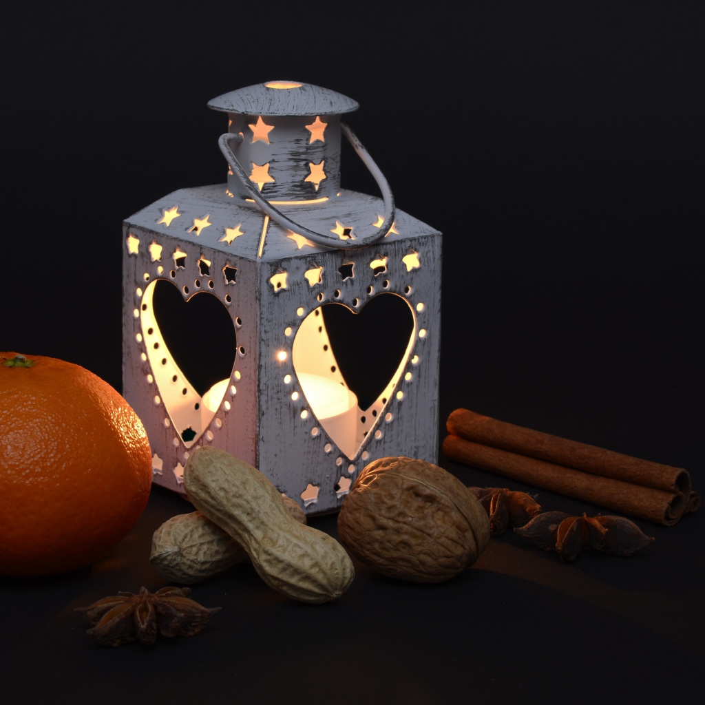 Мандарин, орехи, специи и фонарь на черном фоне