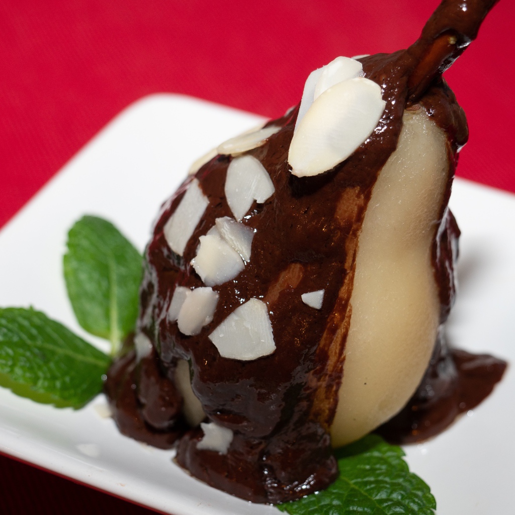 Pear on a white plate with chocolate on a red background